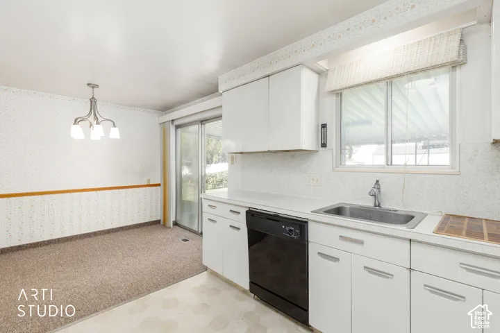 Kitchen featuring white cabinetry and countertops, an integrated stainless steel sink, and a black dishwasher