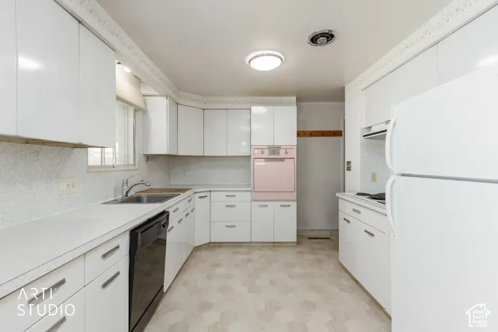 Kitchen featuring white cabinetry, light-toned countertops, a stainless steel sink, and light-colored flooring