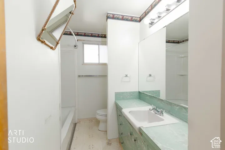 Bathroom featuring a single vanity with an integrated sink, an expansive mirror, a shower-tub combination, and a window