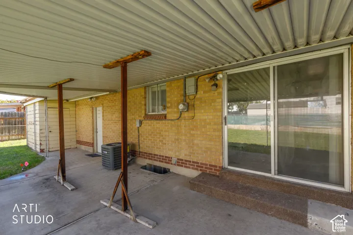 Covered patio with a concrete surface, featuring a brick exterior wall and a large sliding glass door