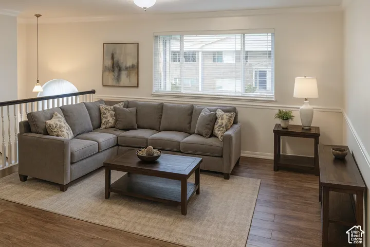 Wood-finish flooring with a neutral area rug, a window with blinds, and white chair rail molding