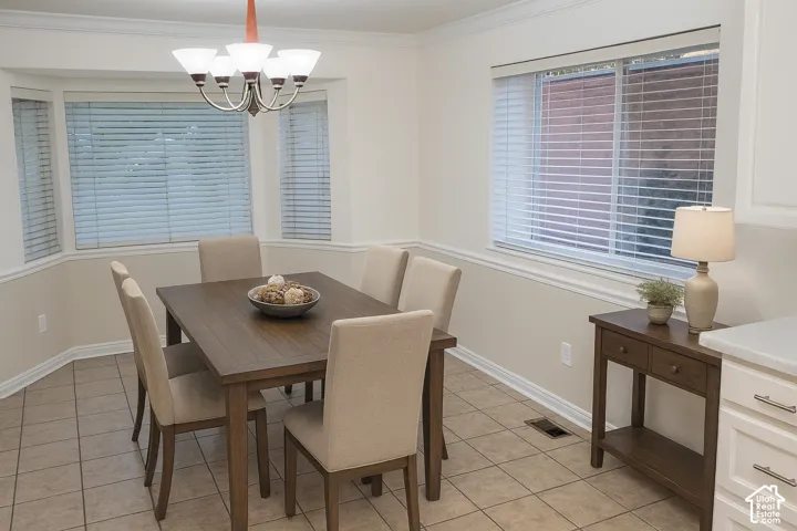Bay window with blinds, tile flooring, crown molding, and a chandelier with frosted glass shades