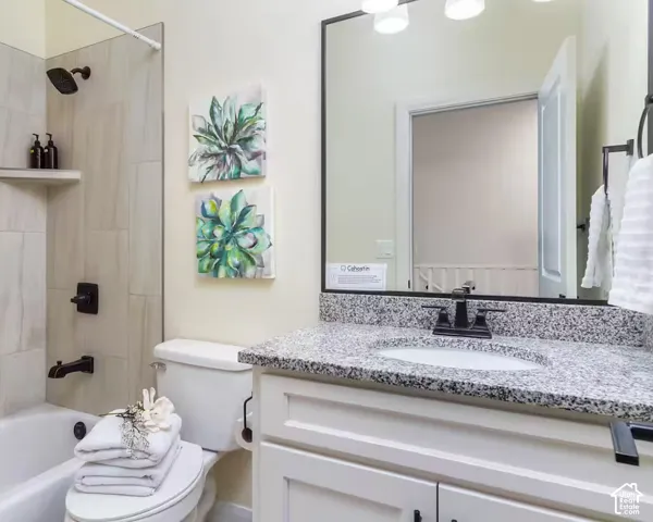 White vanity with a polished stone countertop, rectangular undermount sink, and black faucet