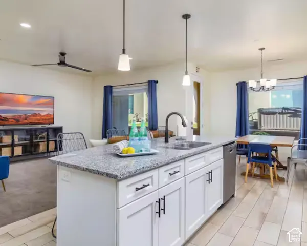 Kitchen island featuring white cabinetry, a granite-finish countertop, and a stainless steel sink with a matte black faucet