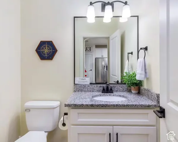 White vanity with shaker-style cabinetry, a granite-finish countertop, and an undermount sink
