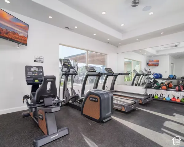 Dedicated fitness area featuring rubberized flooring, large windows, recessed lighting, and a mirrored wall