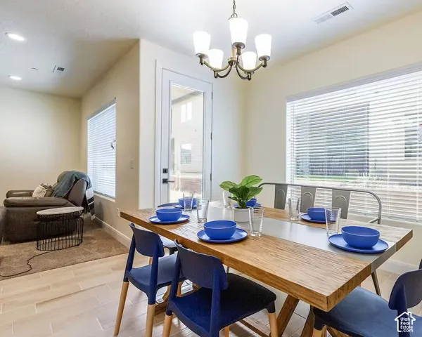 Dining area featuring wood-finish flooring, a contemporary chandelier, and ample natural light through large windows