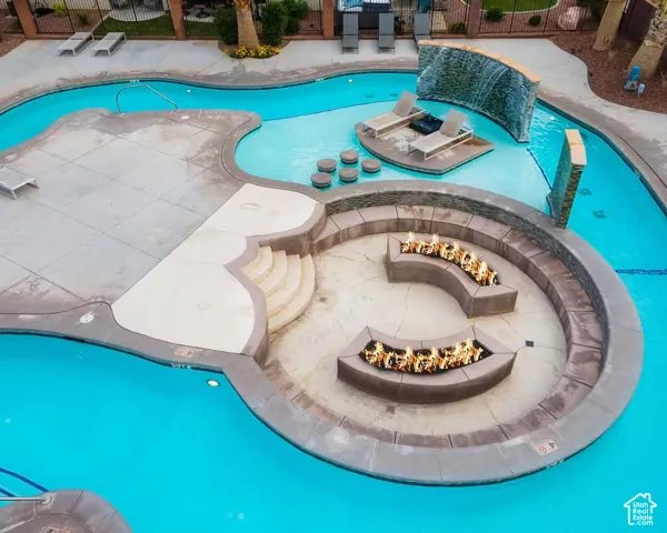Expansive pool area featuring a fire pit with built-in seating, a waterfall feature, and a shallow lounge area