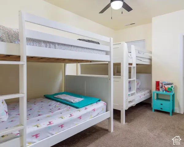 Carpeted room with a ceiling fan, white bunk beds, and a window with blinds