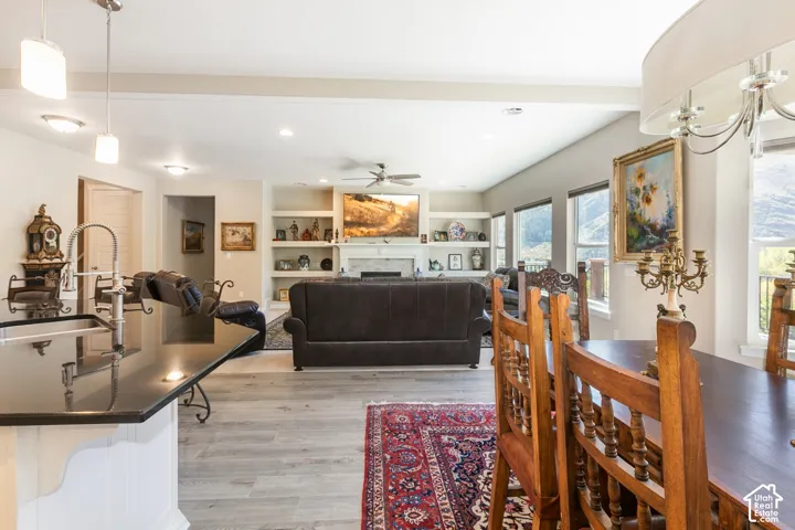 Open-concept living area with wood-finish flooring, a fireplace with built-in shelving, and large windows
