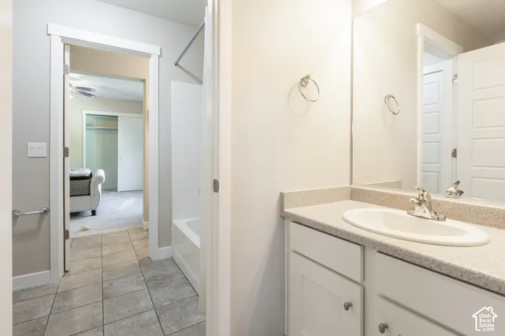 Vanity with integrated sink, expansive mirror, and tile flooring