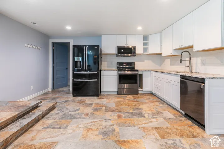 Kitchen featuring white cabinetry, stainless steel appliances, light-toned countertops, white subway tile backsplash, and multi-toned tile flooring