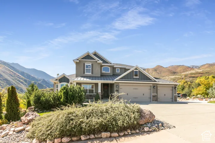 Stucco and siding exterior with stone accents, covered front porch, attached three-car garage, and mature landscaping