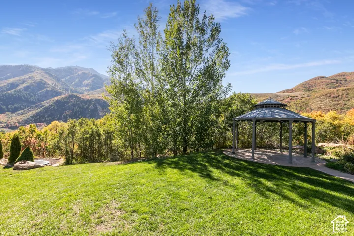 Expansive lawn with a built-in gazebo, complemented by surrounding trees and distant mountains