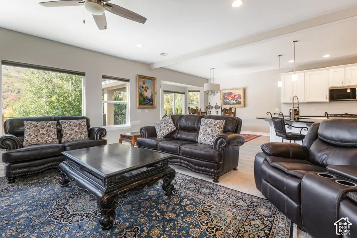 Recessed lighting, wood-finish flooring, ceiling fan, white cabinetry, and a kitchen island with seating