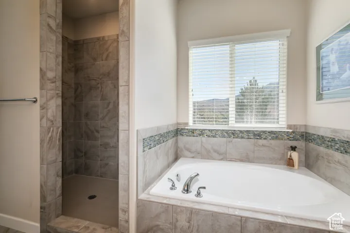 Recessed shower with tile surround, built-in bathtub with tile deck, and decorative mosaic tile accent