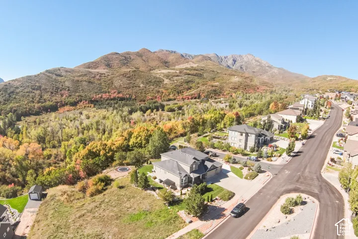 Mountain backdrop with vibrant fall foliage, residential street, and a manicured lawn