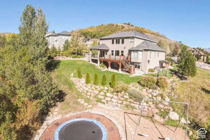 Two-story stucco exterior with a multi-level deck, covered patio, and terraced landscaping