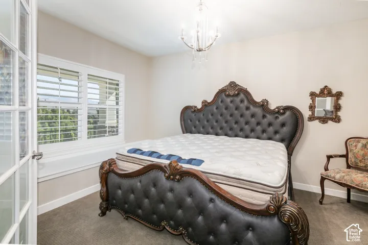 French doors with glass panels, plantation shutters on windows, chandelier with clear accents, and carpeted flooring