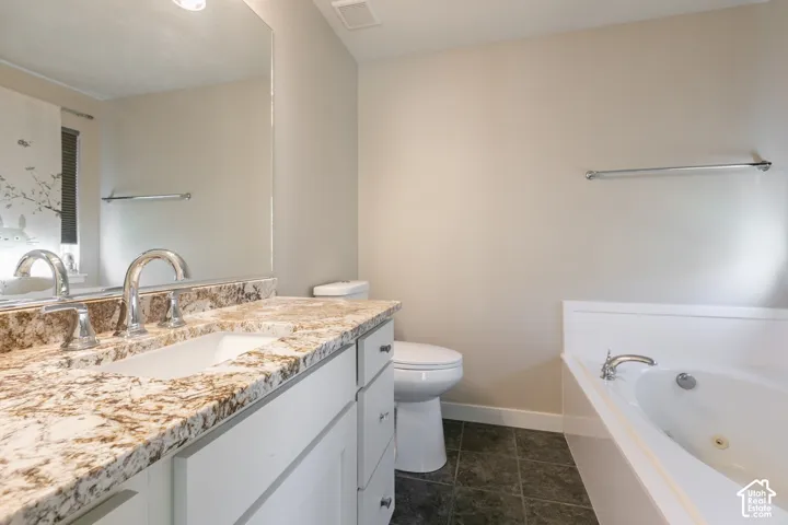 Vanity with a polished chrome faucet, stone-finish countertop, and white cabinetry