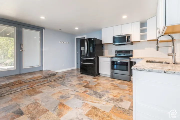 Kitchen featuring white cabinetry, granite countertops, stainless steel appliances, and a subway tile backsplash