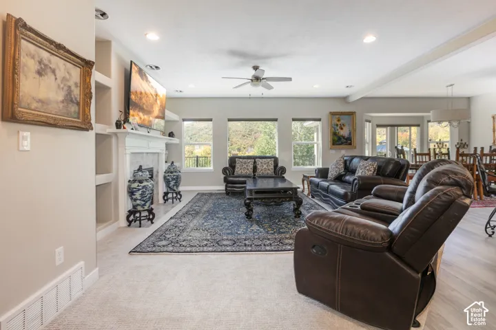 Integrated built-in shelving, a fireplace with a white mantel and marble surround, recessed lighting, and a ceiling fan