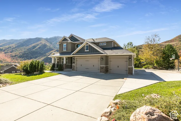Expansive concrete driveway, attached three-car garage, and covered front porch with stone accents