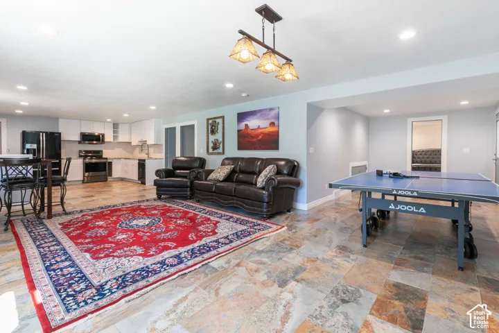 Spacious interior featuring a full kitchen with stainless steel appliances and white cabinetry, stone-finish flooring, and recessed lighting