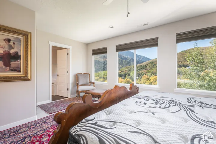 Expansive windows showcasing mountain scenery, light-colored wall paint, ceiling fan, and classic paneled interior doors