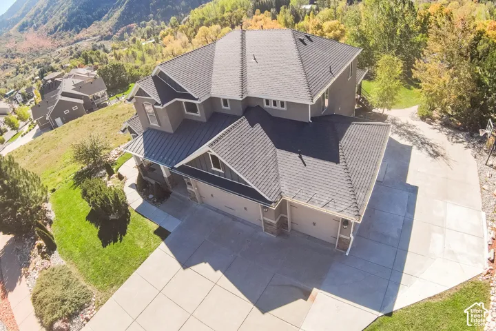 Multi-level residence featuring a gray exterior, dark shingle roof, and a multi-car garage with overhead doors