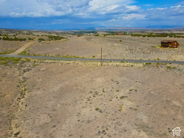 Expansive undeveloped land featuring a paved road frontage and a gravel road access point