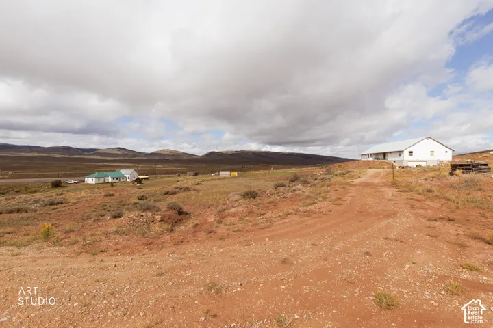 Expansive rural property featuring a large white outbuilding, a smaller structure with a green roof, and a gravel road