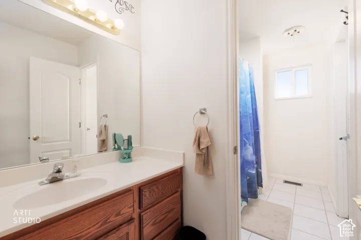 Wood-finish vanity with an integrated sink, polished chrome faucet, and expansive wall mirror