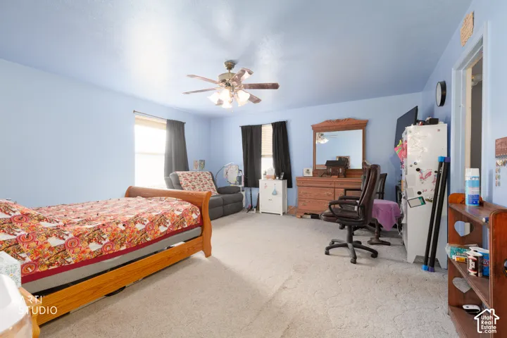 Carpeted interior with light blue walls, two windows with black blinds, and a ceiling fan with integrated lighting
