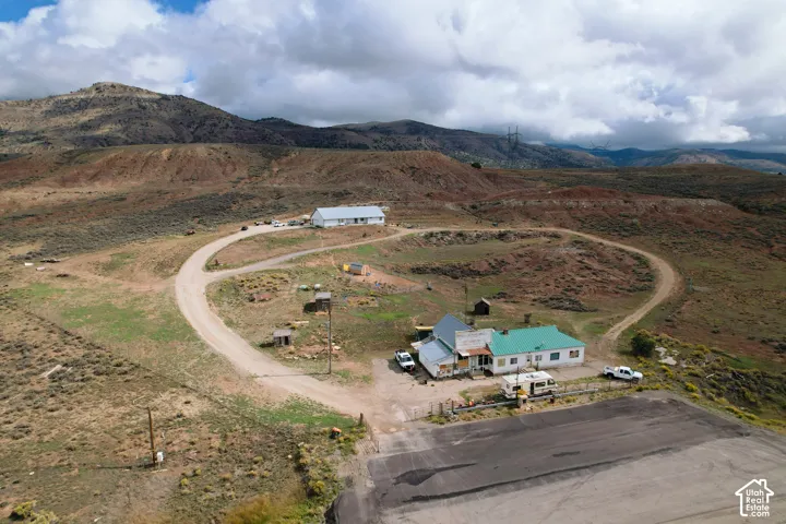 Expansive land with multiple structures, including a primary residence with a green roof, a separate larger building with a white roof, and multiple outbuildings