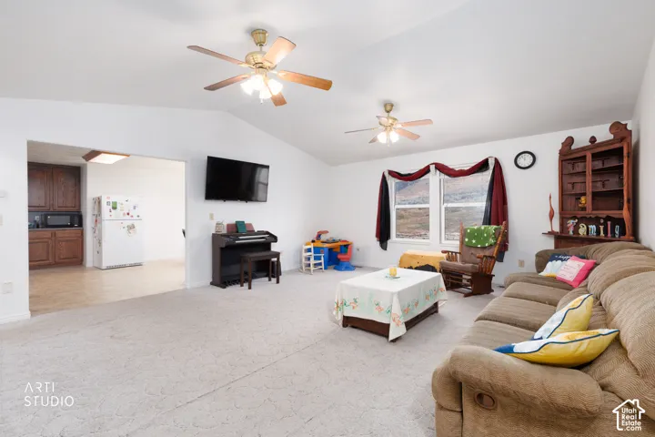 Open living space with vaulted ceilings and two ceiling fans