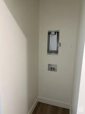 Laundry hookups with wood-finish flooring and a wall outlet