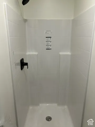 Shower stall with a black shower head, coordinating black single-handle shower valve, integrated shelving, and a textured white surround
