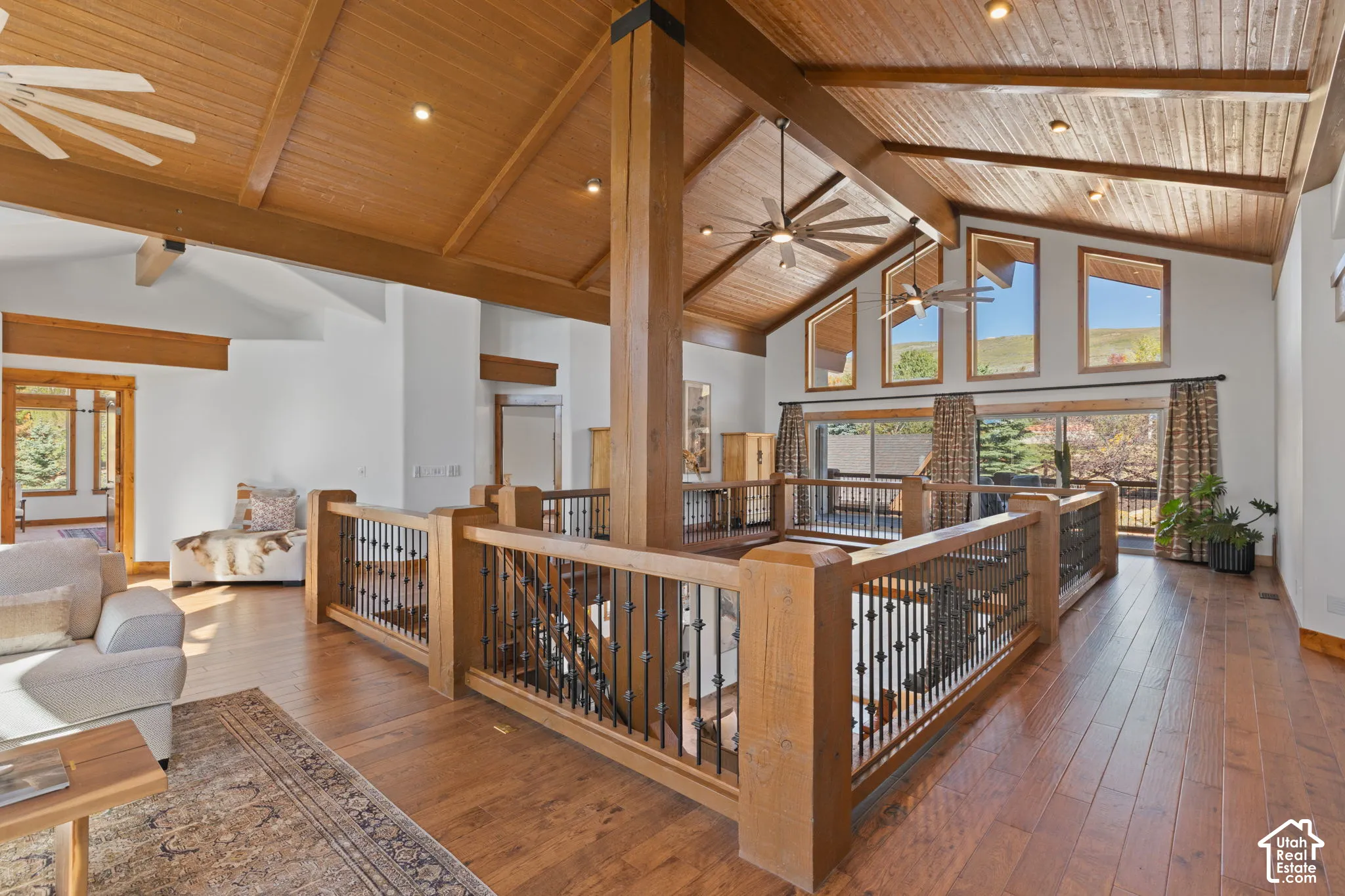 Vaulted wood-paneled ceilings with exposed beams, wood-finish flooring, and wood stair railing with decorative metal balusters