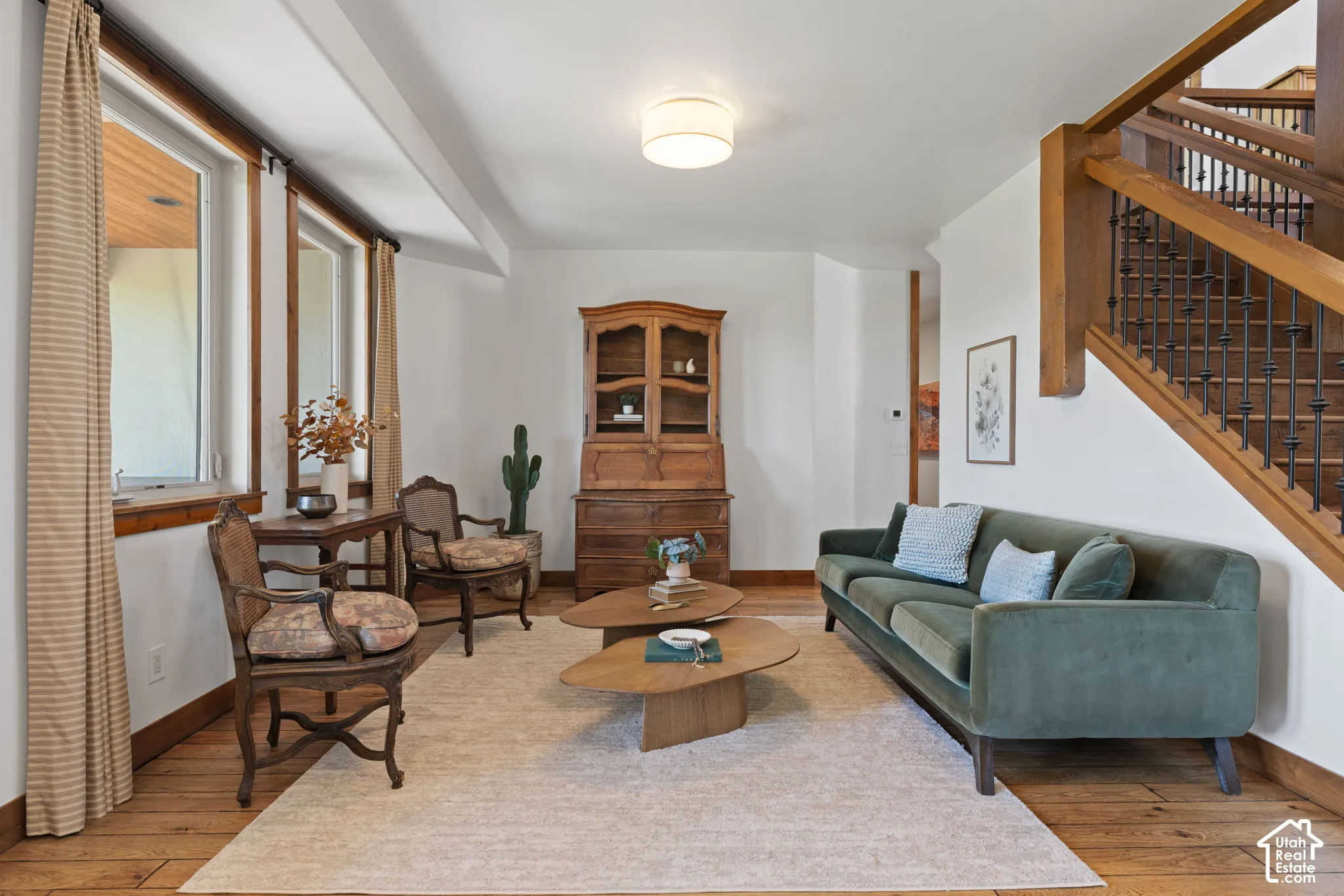 Hardwood flooring, white walls, and a wood-finish staircase with wrought iron balusters