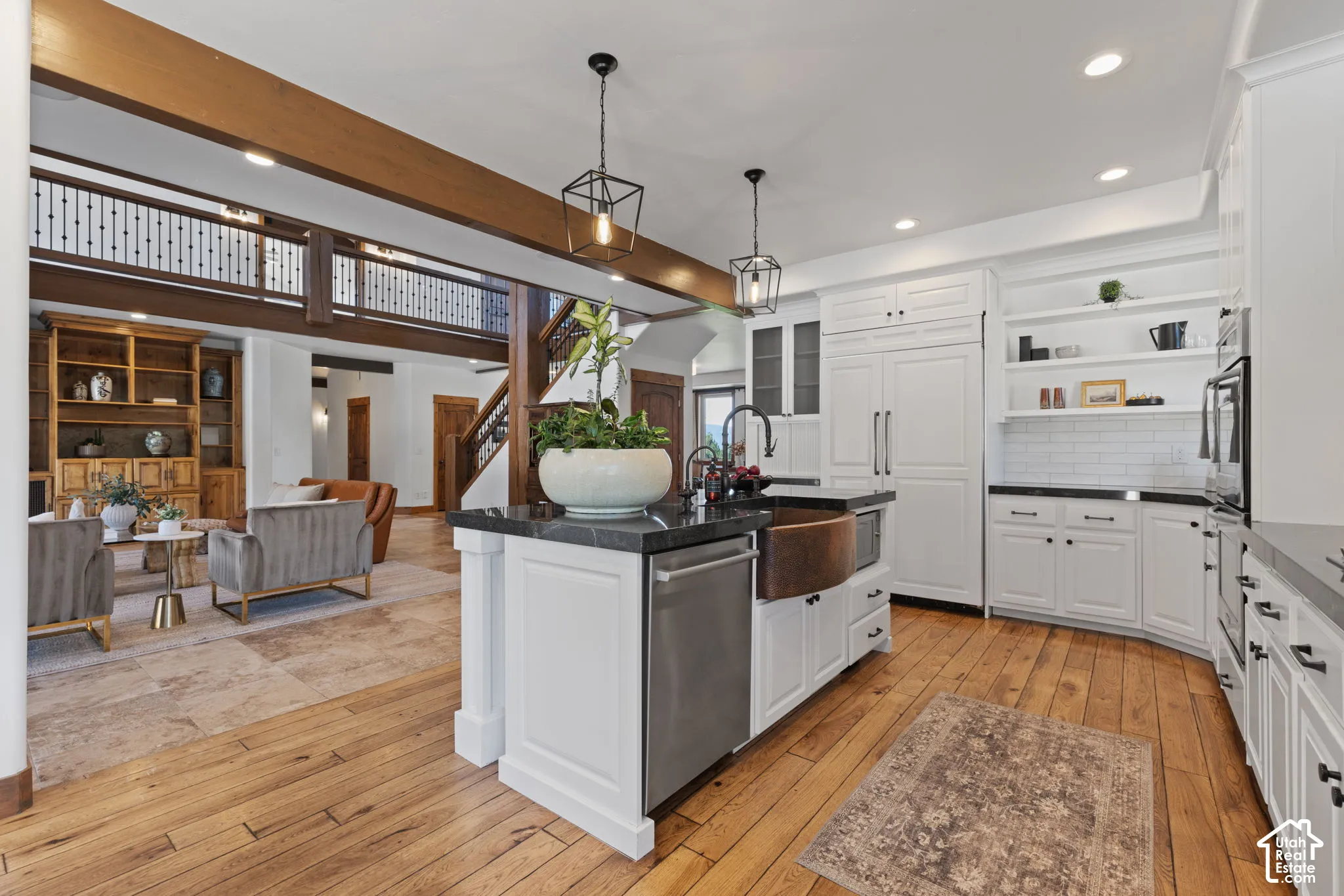 White cabinetry with dark hardware, stone countertops, wood-finish flooring, subway tile backsplash, and a copper-toned basin sink