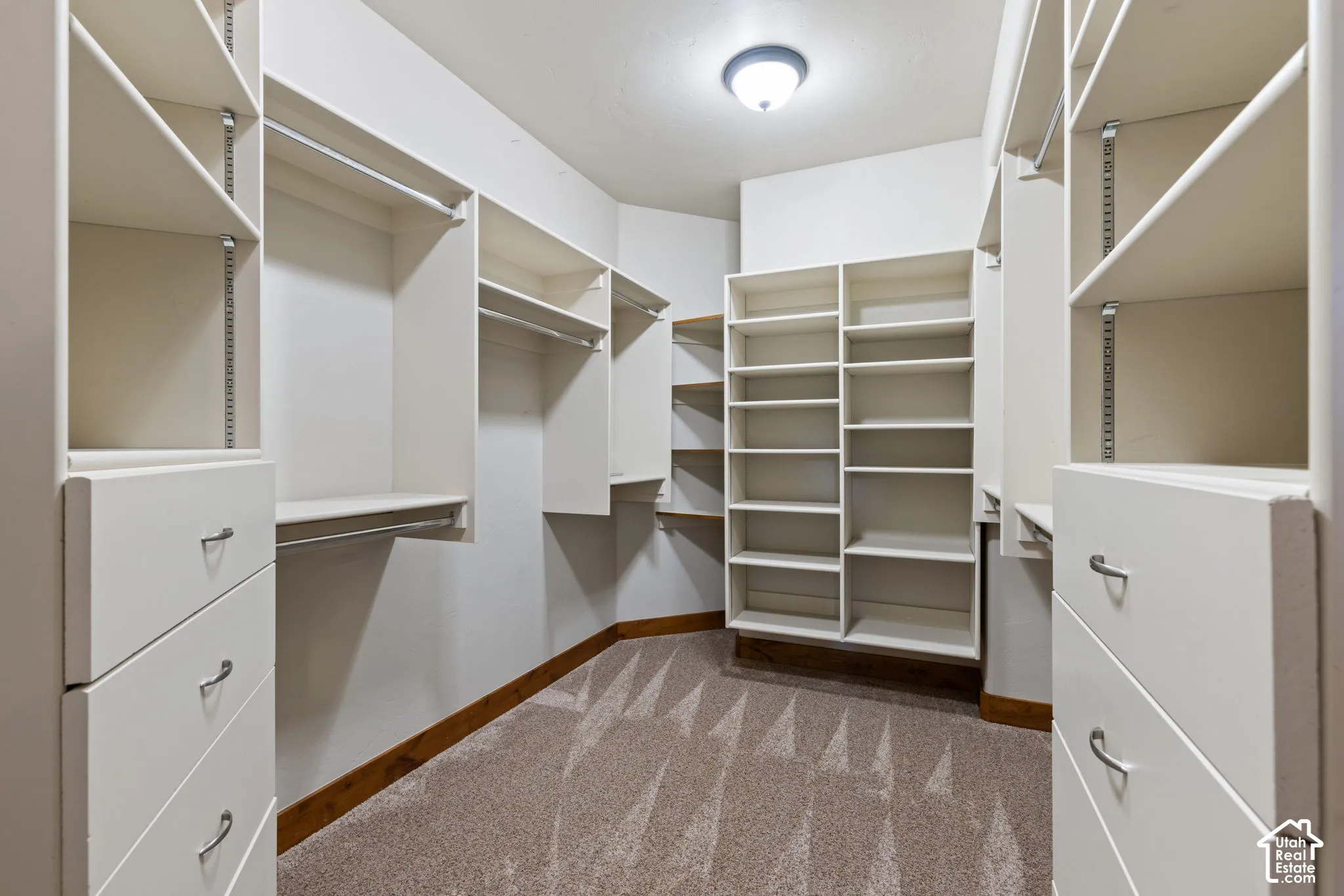 Custom closet system featuring multiple hanging rods, built-in shelving, integrated drawers, and neutral carpeting