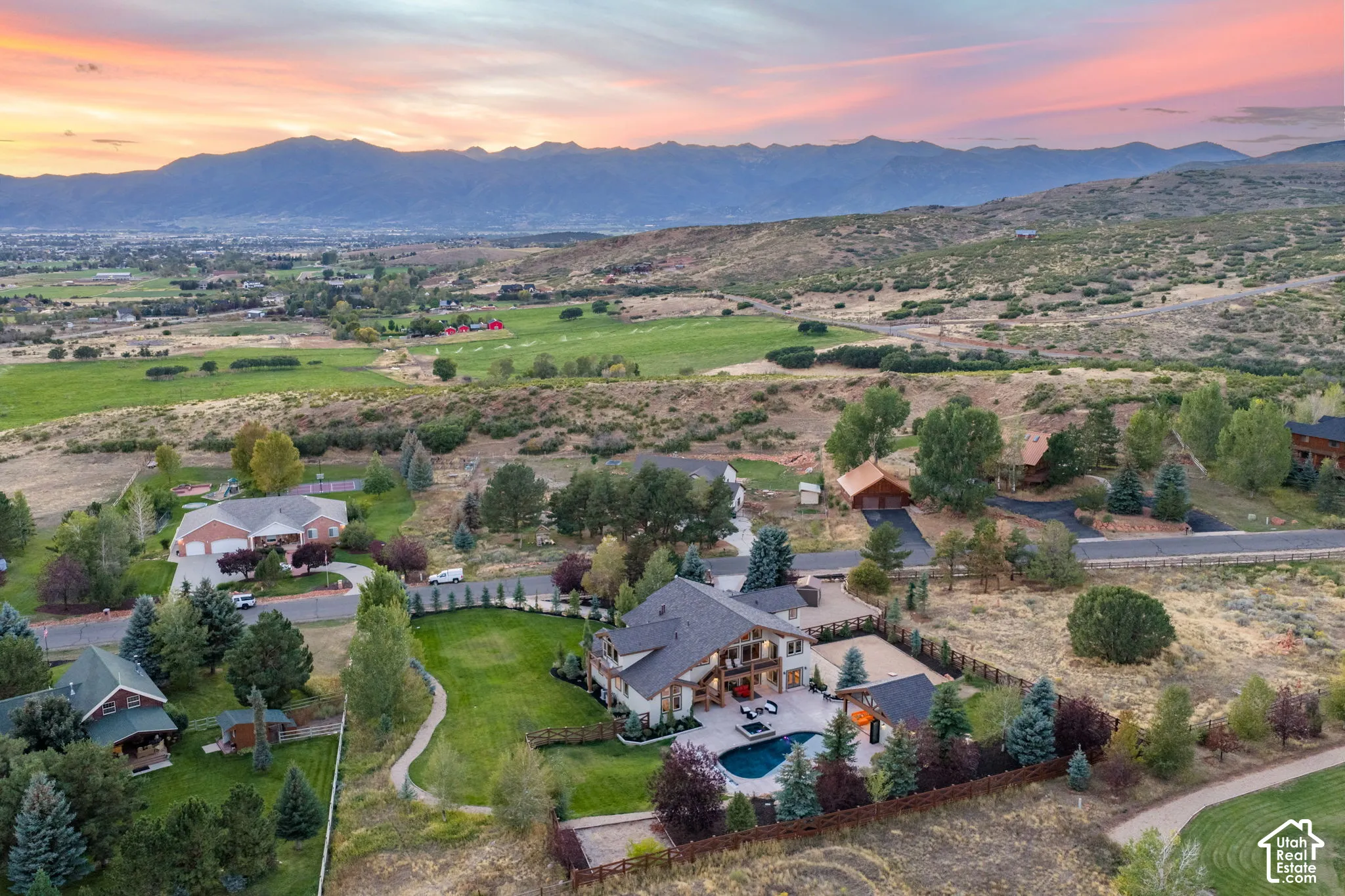 Expansive property with a large swimming pool, surrounding paved patio, and a manicured lawn