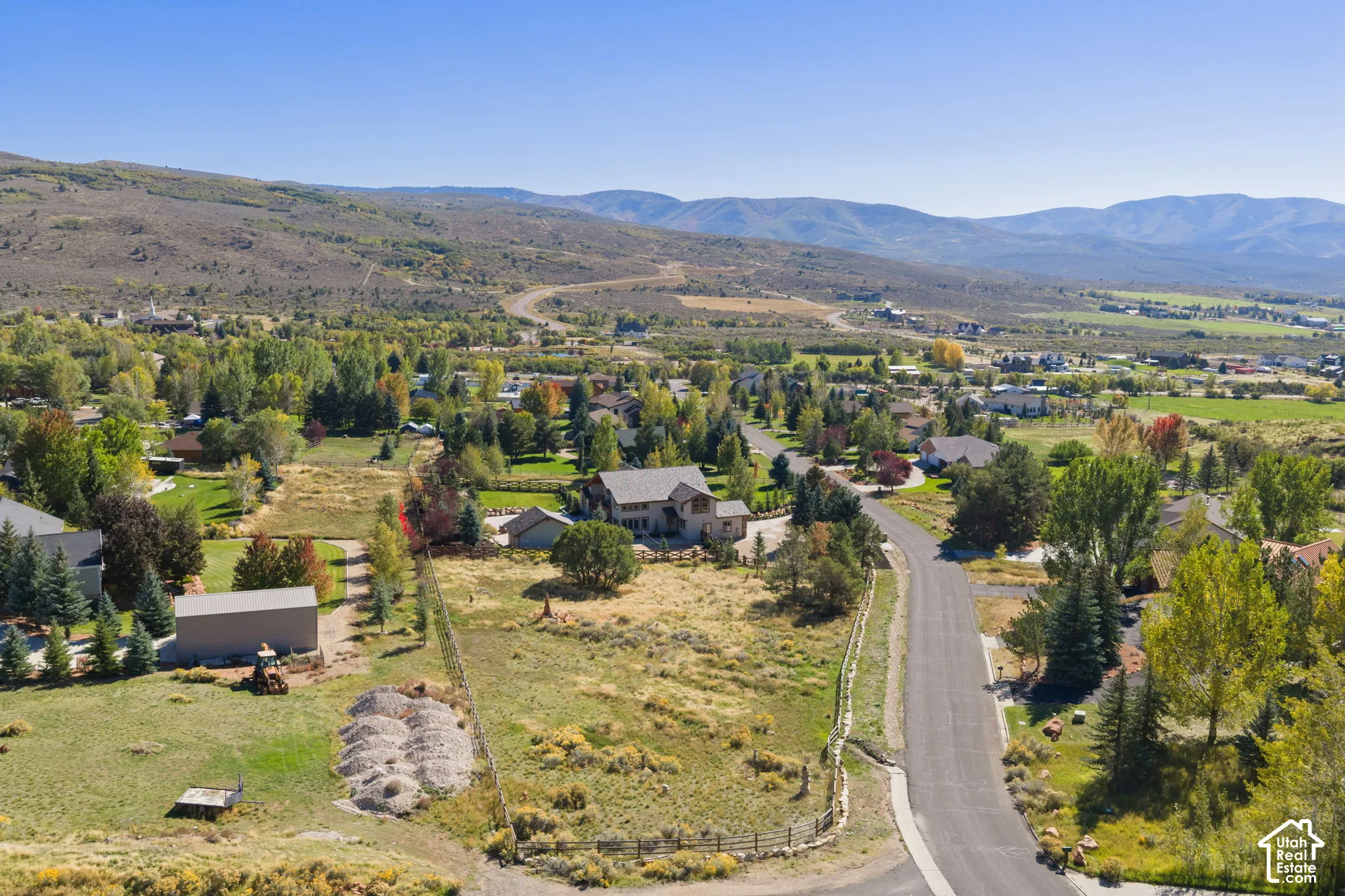 Expansive open land with a paved road, scattered mature trees, and distant mountain backdrops