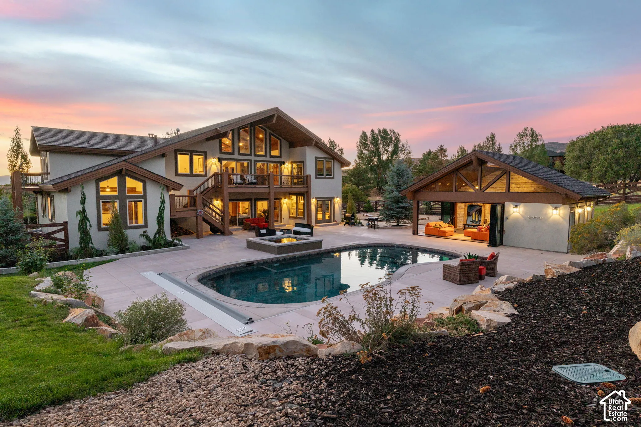 Expansive outdoor living area featuring a freeform swimming pool, integrated fire pit, and a detached gabled structure with exposed wooden beams