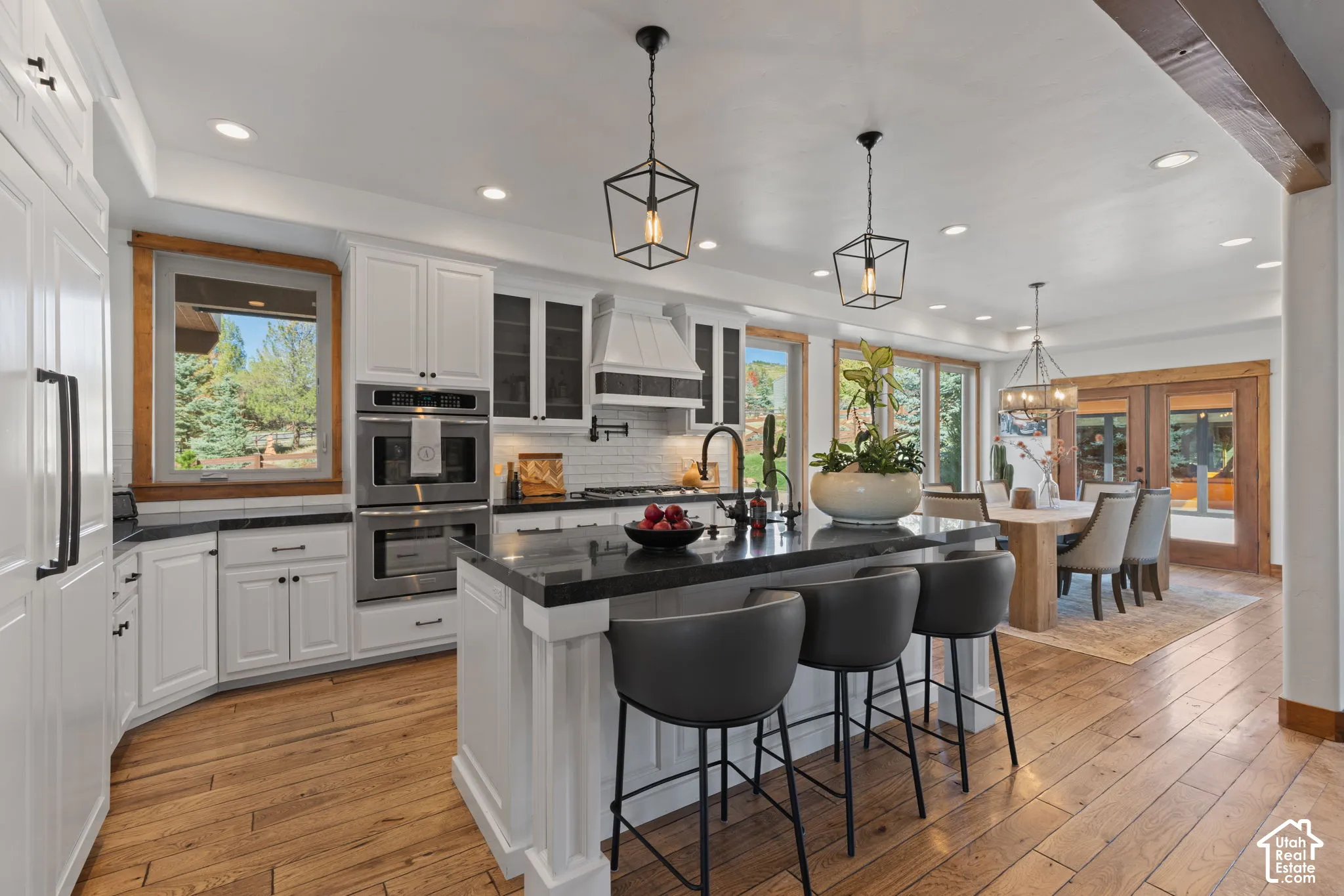 Gourmet kitchen with wood-finish flooring, white cabinetry, dark countertops, and stainless steel double ovens