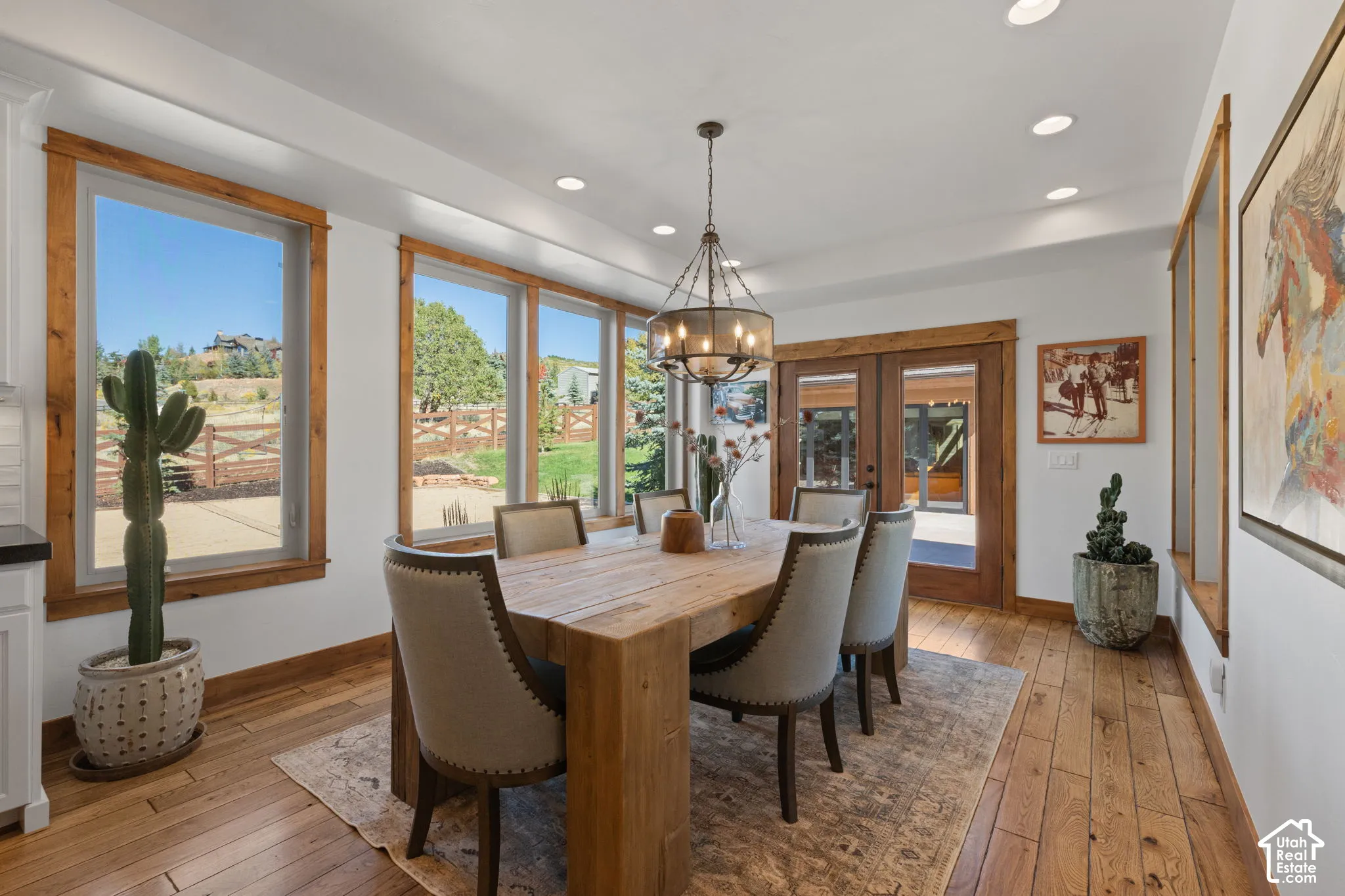 Hardwood flooring, recessed ceiling lighting, wood-trimmed windows, a multi-light chandelier, and double paneled doors
