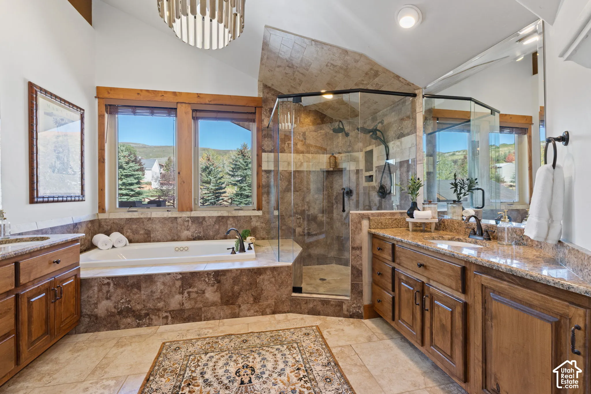 Spacious bathroom featuring a built-in soaking tub, a walk-in shower with glass enclosure, two wood vanities with undermount sinks, and a circular overhead light fixture