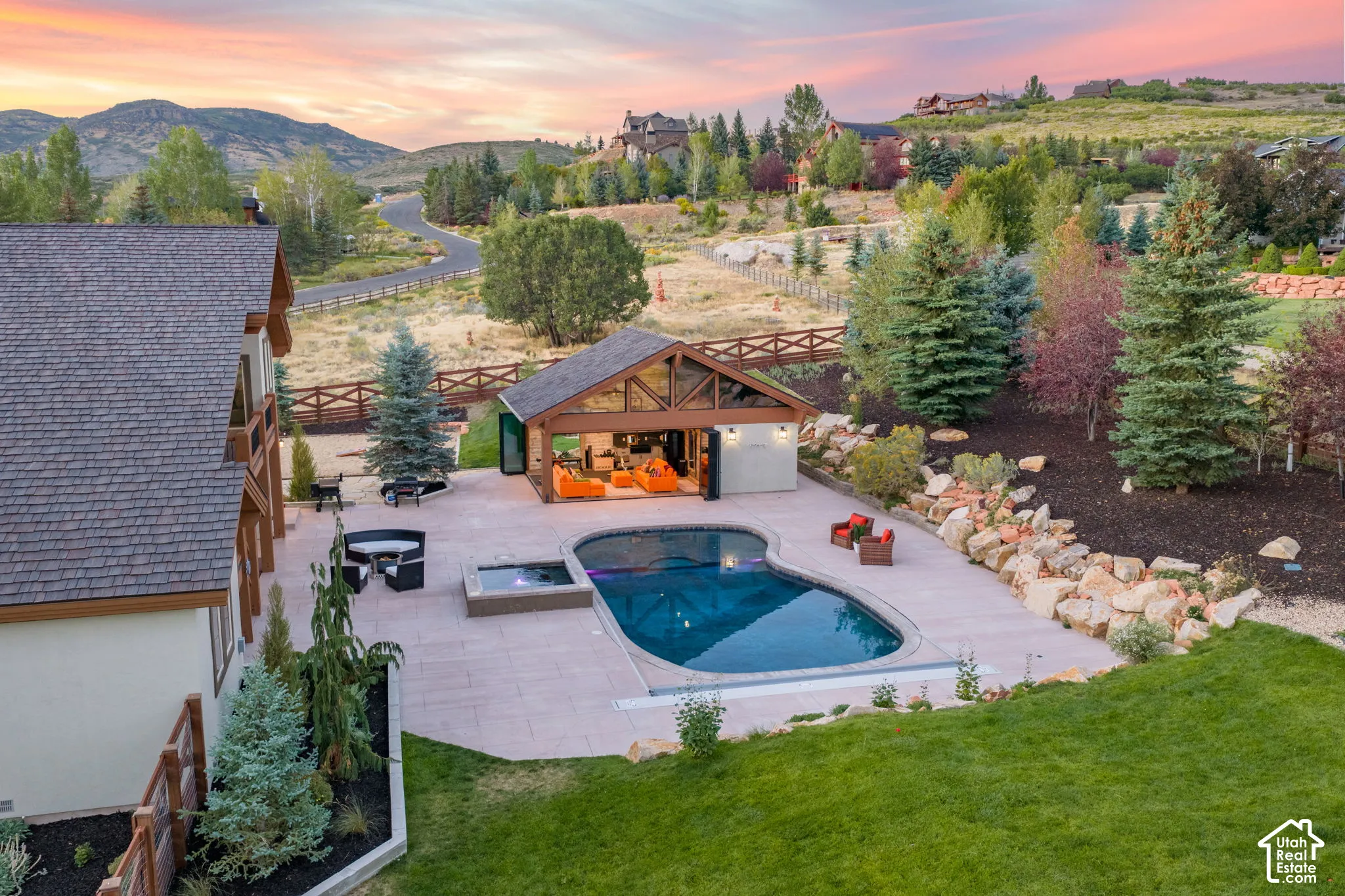 Outdoor pool with integrated spa, expansive paved patio, and a covered pavilion featuring a vaulted ceiling
