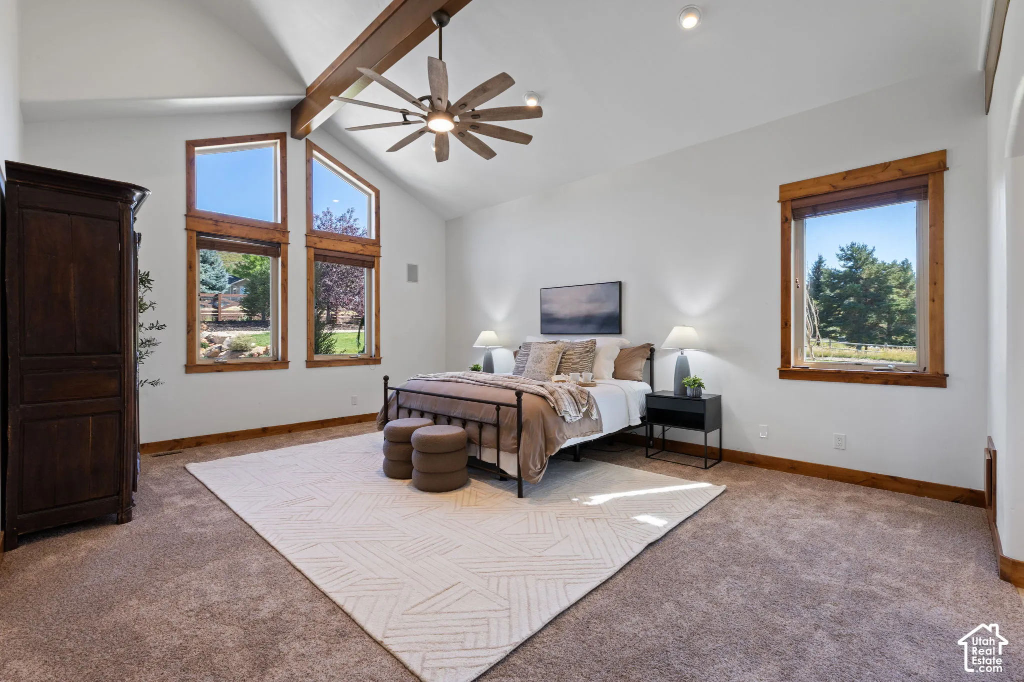Vaulted ceiling with exposed wood beam, ceiling fan, multiple large windows with wood trim, and recessed lighting